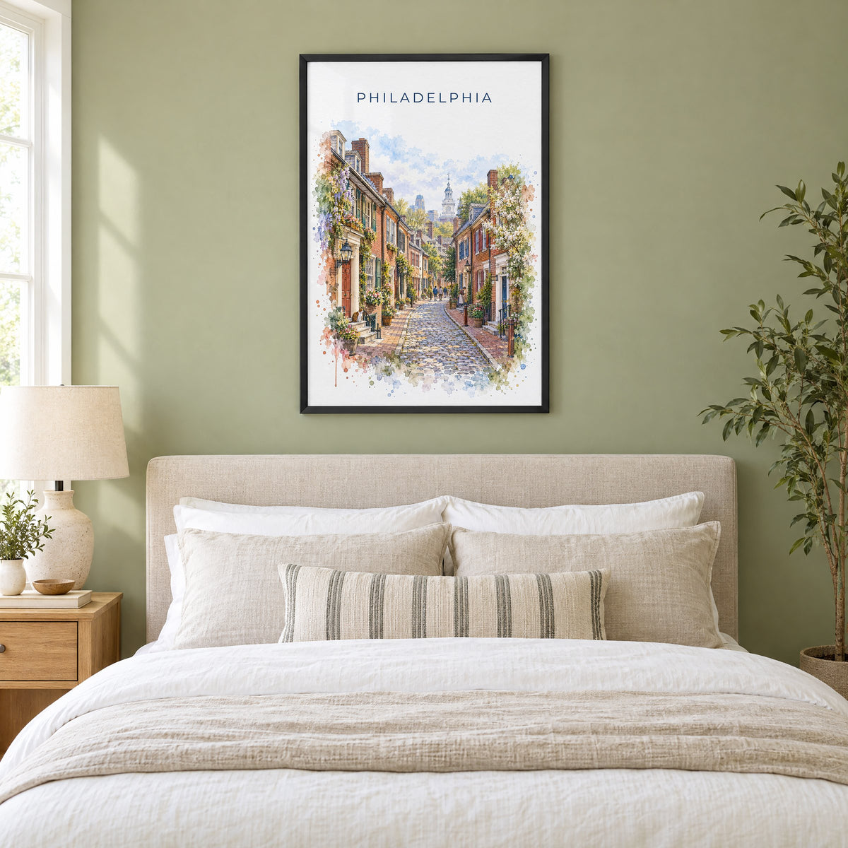 Elfreth's Alley Philadelphia watercolor print in a black frame above an upholstered headboard in a sage green bedroom