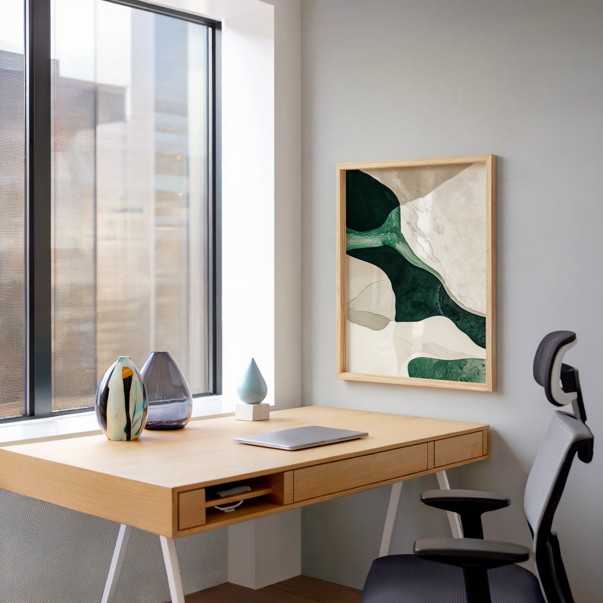 Emerald and cream organic shapes abstract print in a pale wood frame above a home office desk by a tall window