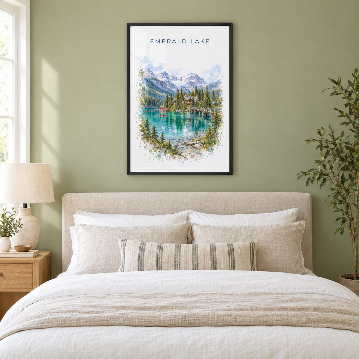 Emerald Lake, BC watercolor print in a black frame above an upholstered headboard in a sage green bedroom