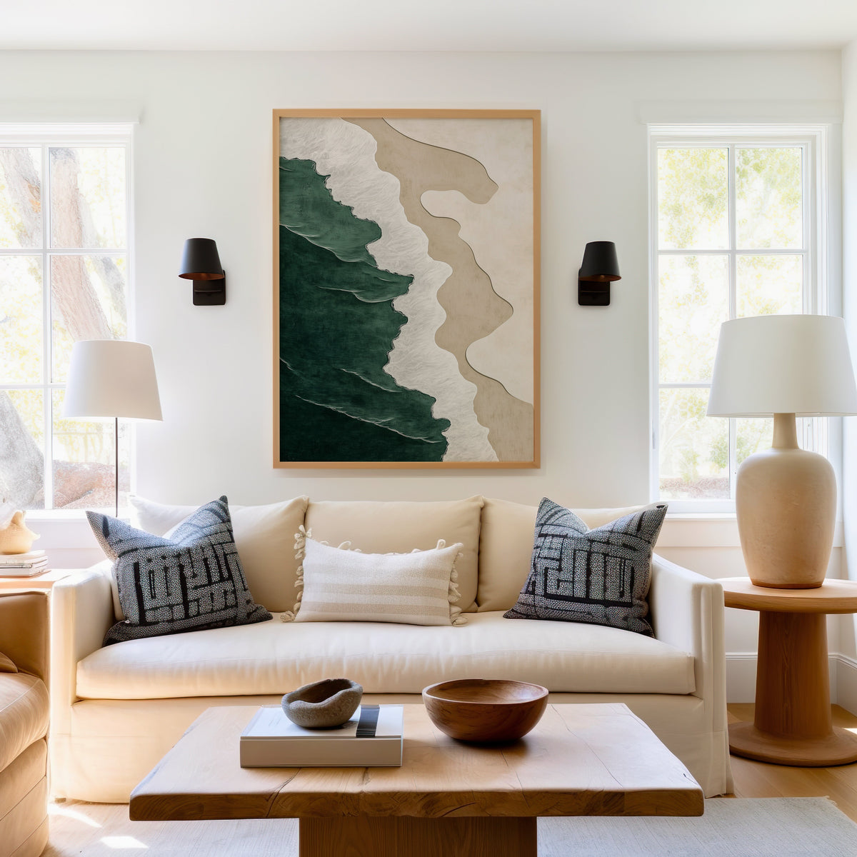 Emerald, white and sand shoreline abstract print in a light oak frame above a cream sofa between two black wall sconces
