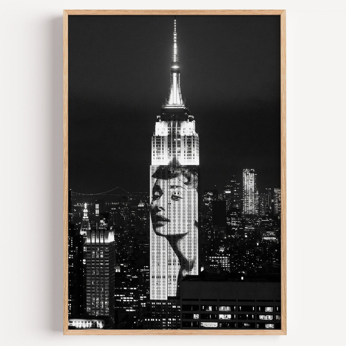 Empire State Building at night with projected face print in a light oak frame on a plain white wall