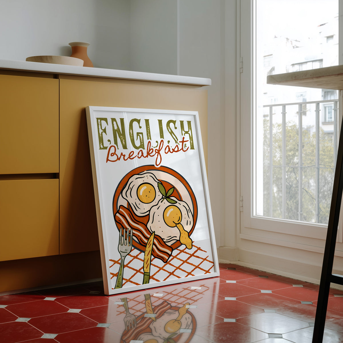 English breakfast print in a white frame against yellow cabinets on a red tiled floor