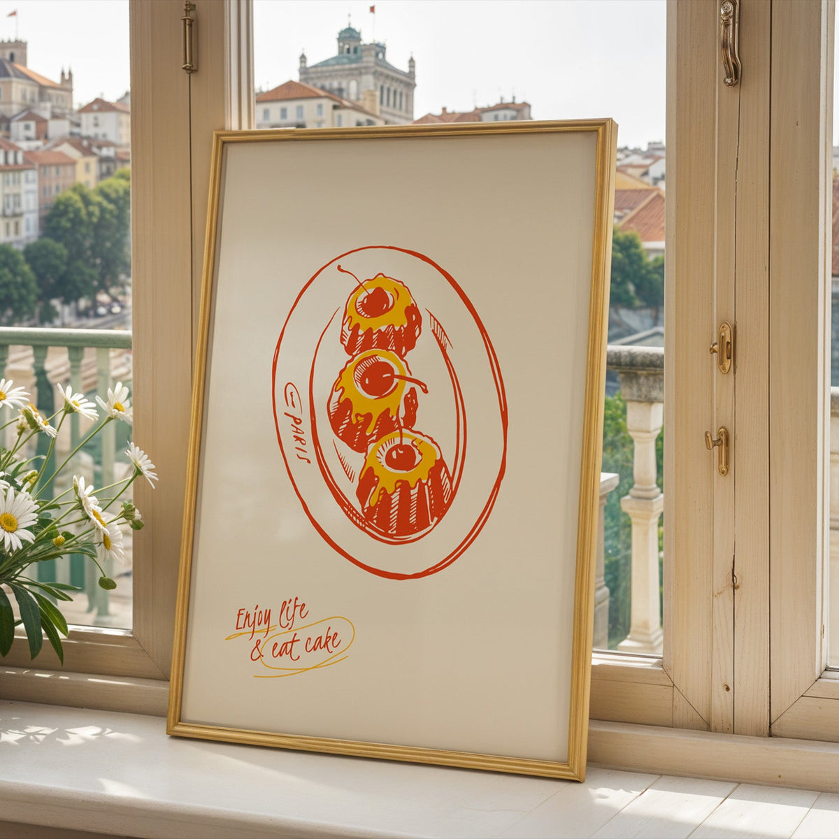 Enjoy Life and Eat Cake print in a gold frame on a window sill above a hillside town
