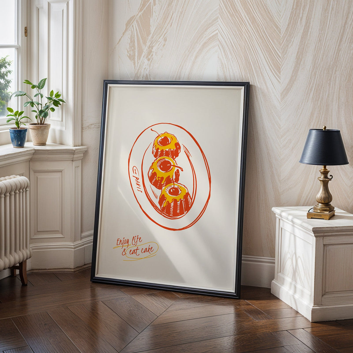 Enjoy Life and Eat Cake print in a black frame on a dark herringbone floor