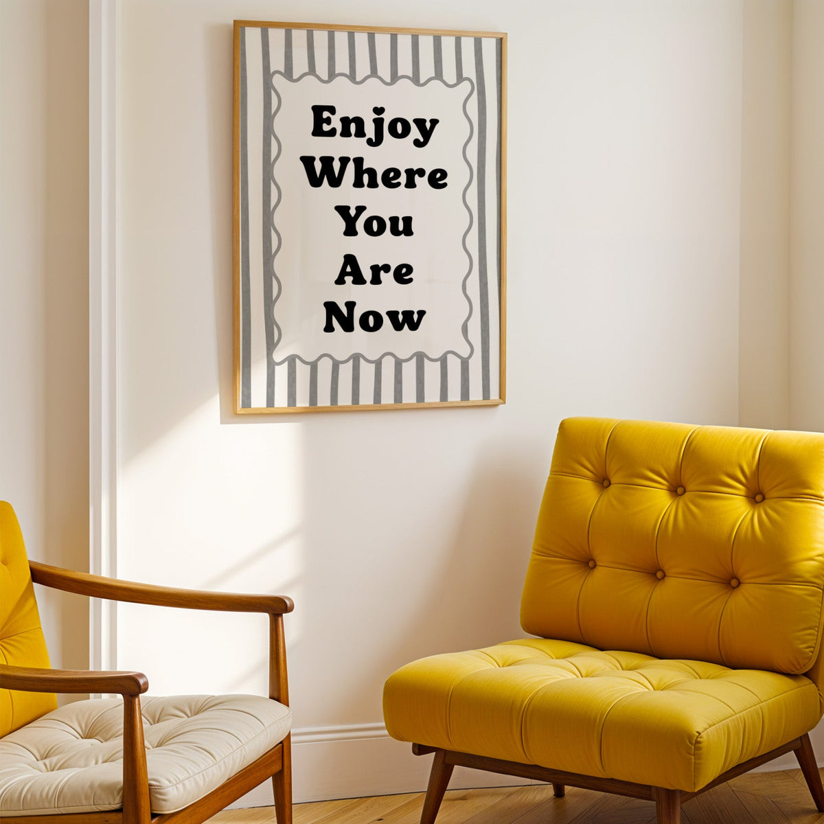 Enjoy where you are now striped quote print shown in a gold frame above a mustard yellow tufted armchair