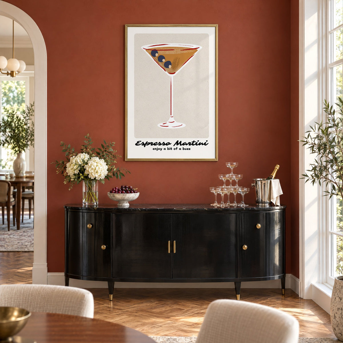 Espresso Martini cocktail glass print in a brass frame on a terracotta wall above a black buffet with a champagne tower