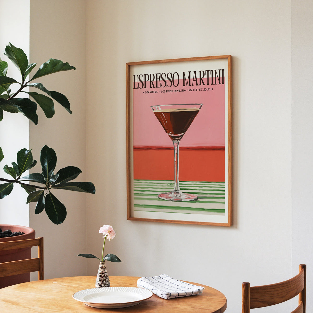 Espresso martini recipe print in a walnut frame above a round table beside a fiddle-leaf fig
