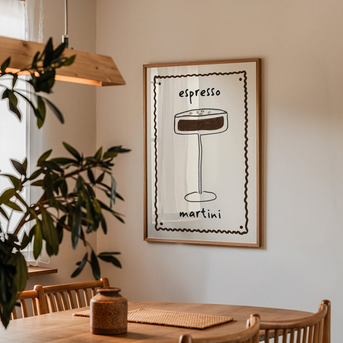 Espresso martini pencil line print in a walnut frame above a dining table beside an olive tree