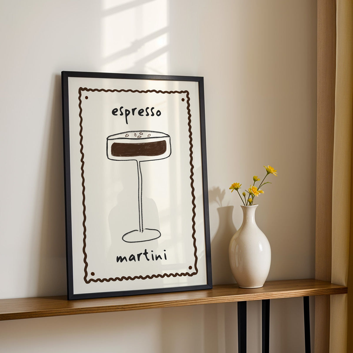 Espresso martini pencil line print in a black frame on a console table with yellow daisies