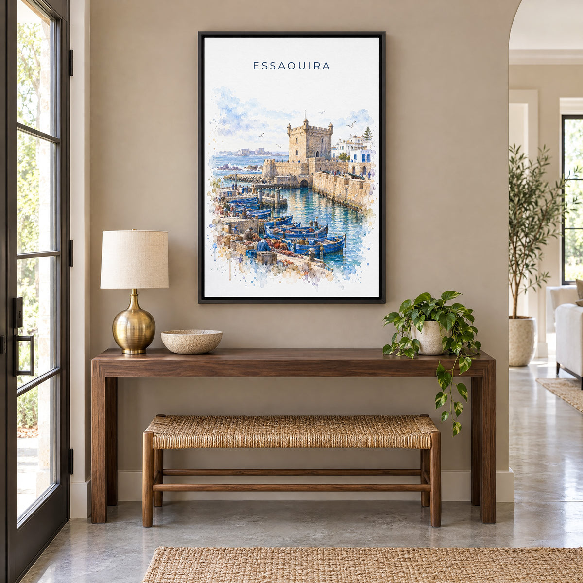 Essaouira watercolor print as a black floater canvas above a walnut console and woven bench in an entryway