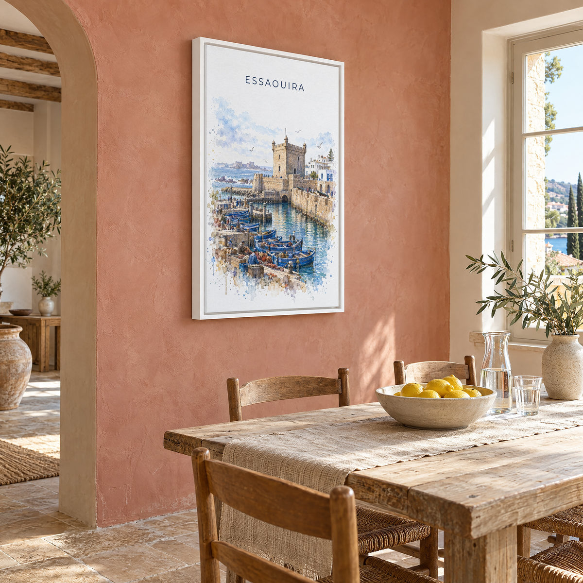 Essaouira watercolor print as a white floater canvas on a terracotta wall above a rustic dining table