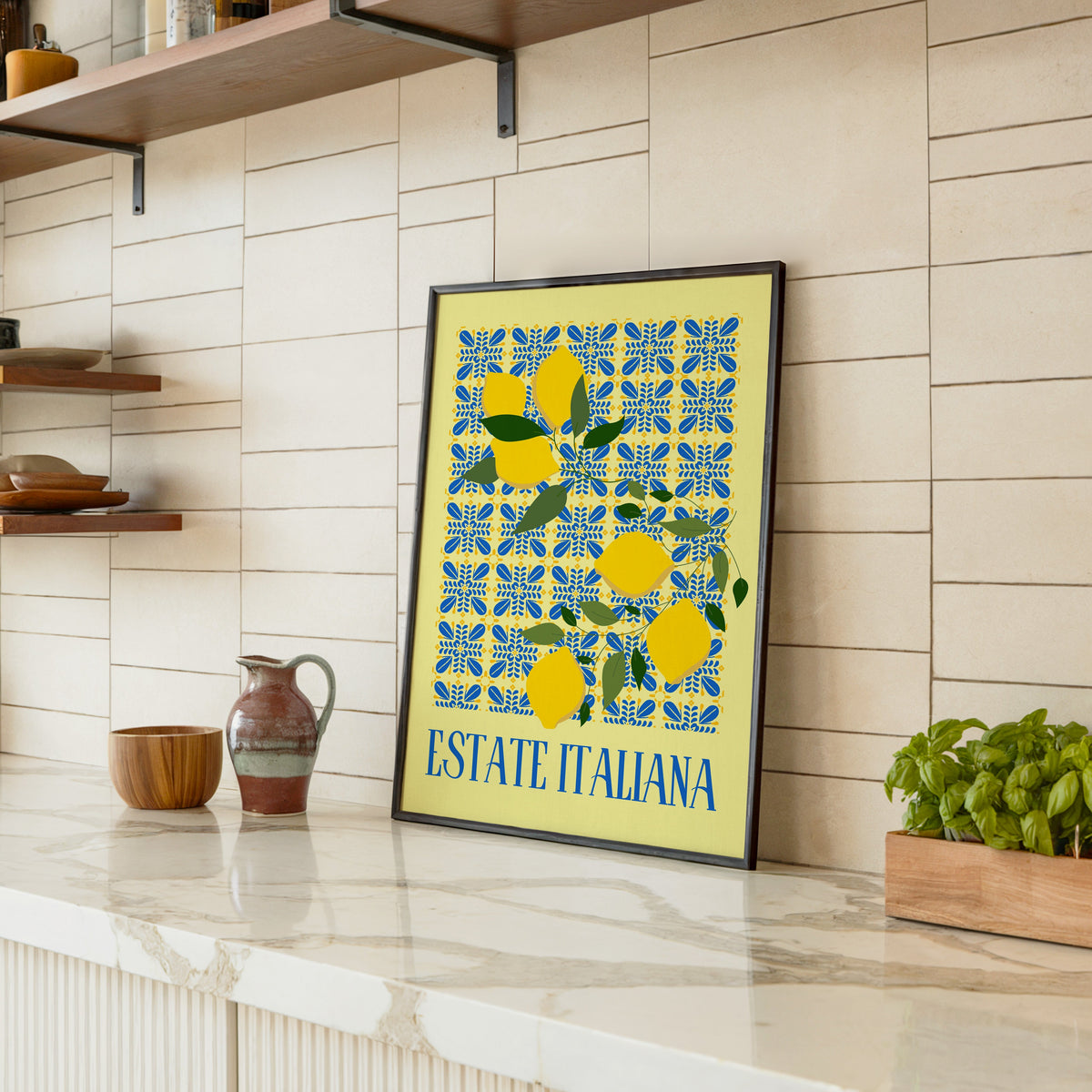 Estate Italiana lemon print in a black frame leaning on a marble counter in a tiled kitchen