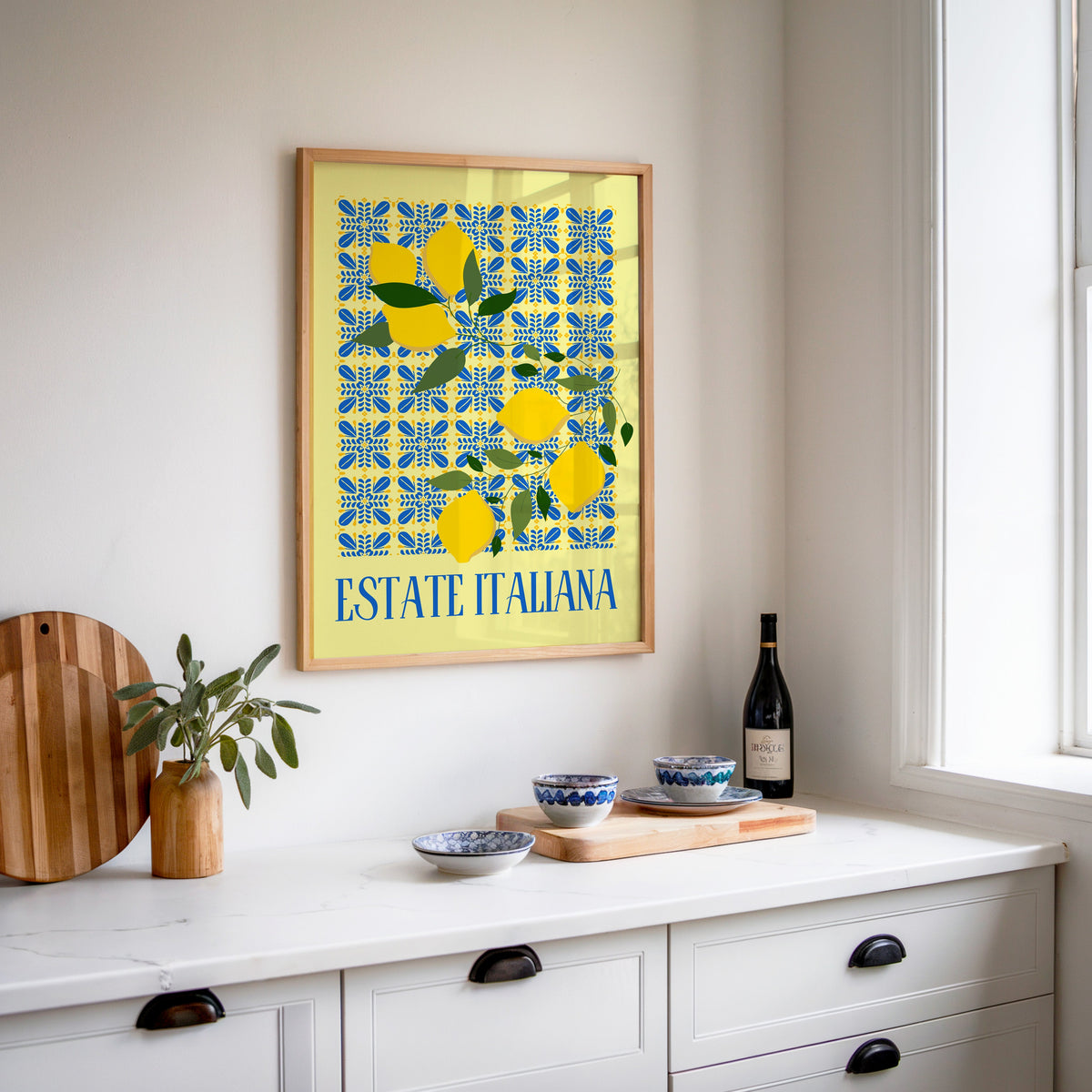 Estate Italiana lemon print in an oak frame above a white sideboard with a bottle of wine