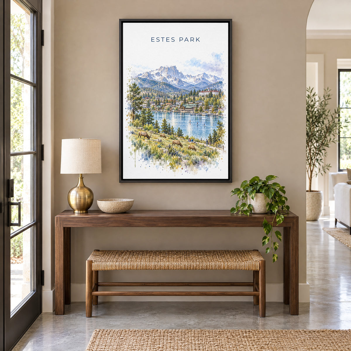 Estes Park watercolor print as a black floater canvas above a walnut console and woven bench in an entryway