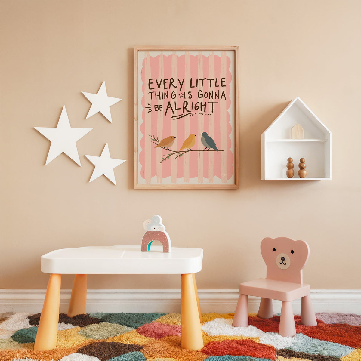 Every little thing birds quote nursery print in an oak frame on a peach wall above a kids table with wall stars