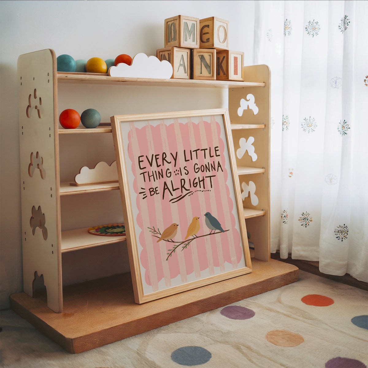 Every little thing birds quote nursery print in an oak frame leaning on a toy shelf with wooden letter blocks