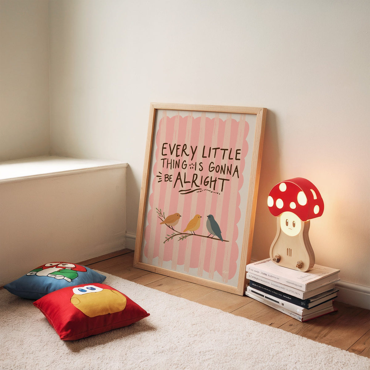 Every little thing birds quote nursery print in an oak frame leaning on a rug beside a mushroom lamp and floor cushions