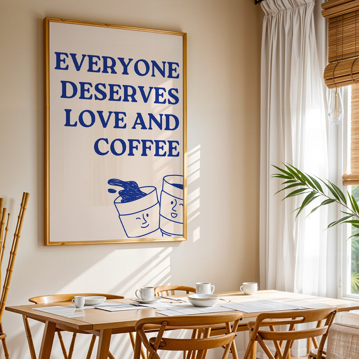 Everyone Deserves Love and Coffee print shown in a gold frame above a breakfast table by a curtained window