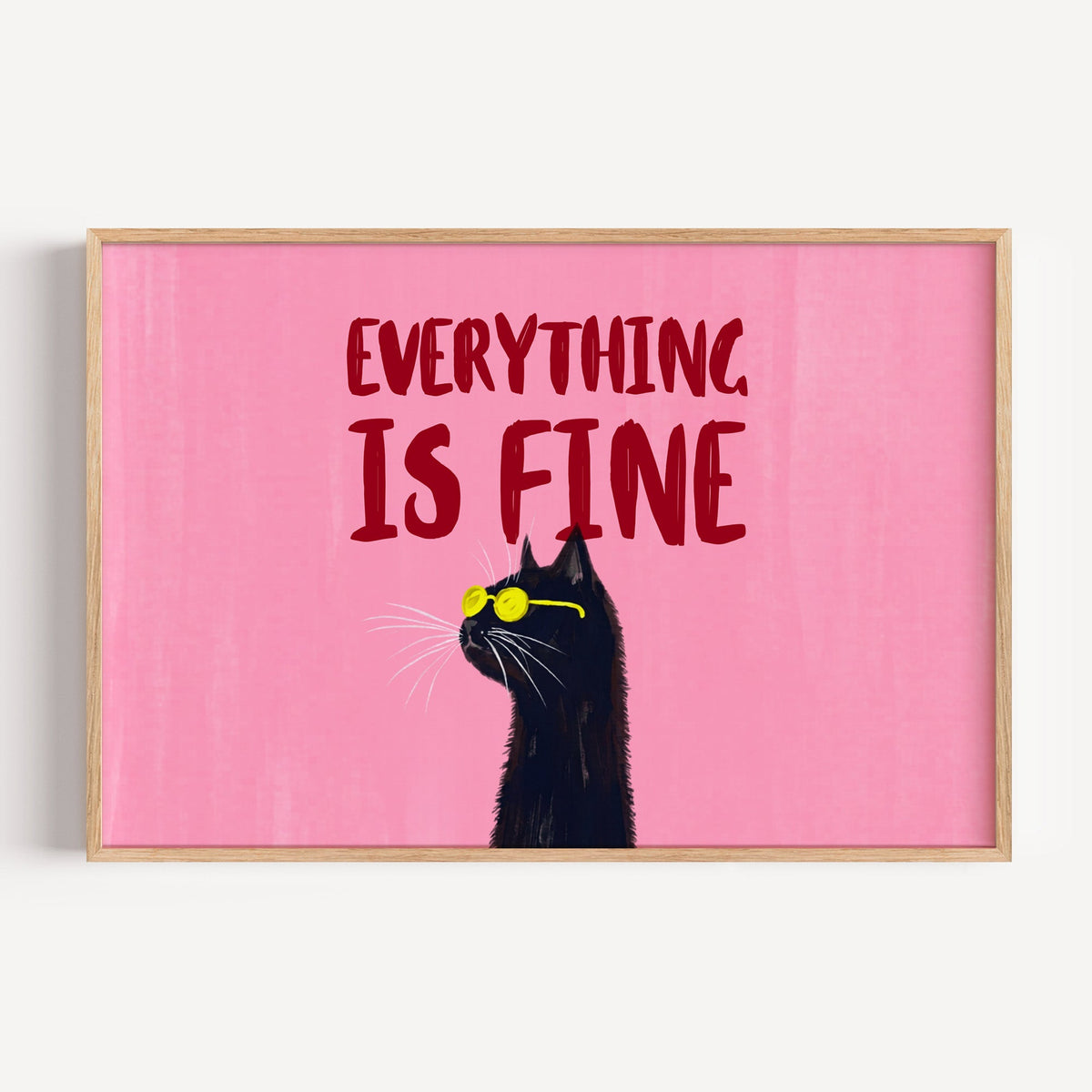 Everything Is Fine cat wide print in a light oak frame on a plain white wall