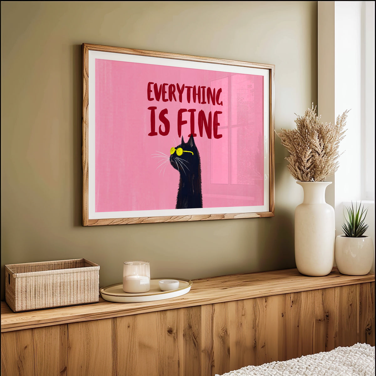 Everything Is Fine cat wide print in an oak frame on an olive green wall above pampas grass