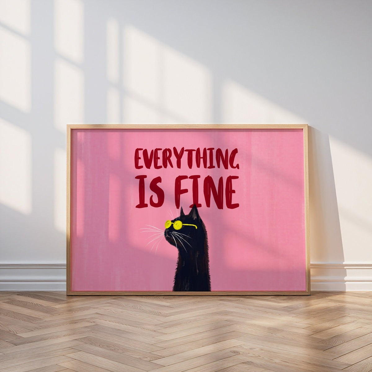 Black cat quote print in an oak frame leaning on a parquet floor in window light