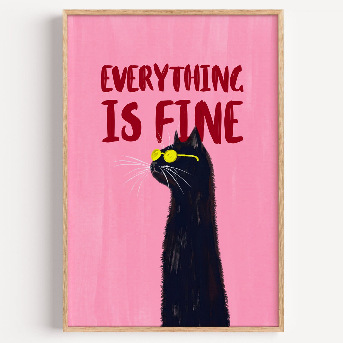 Everything Is Fine black cat print in a light oak frame on a plain white wall