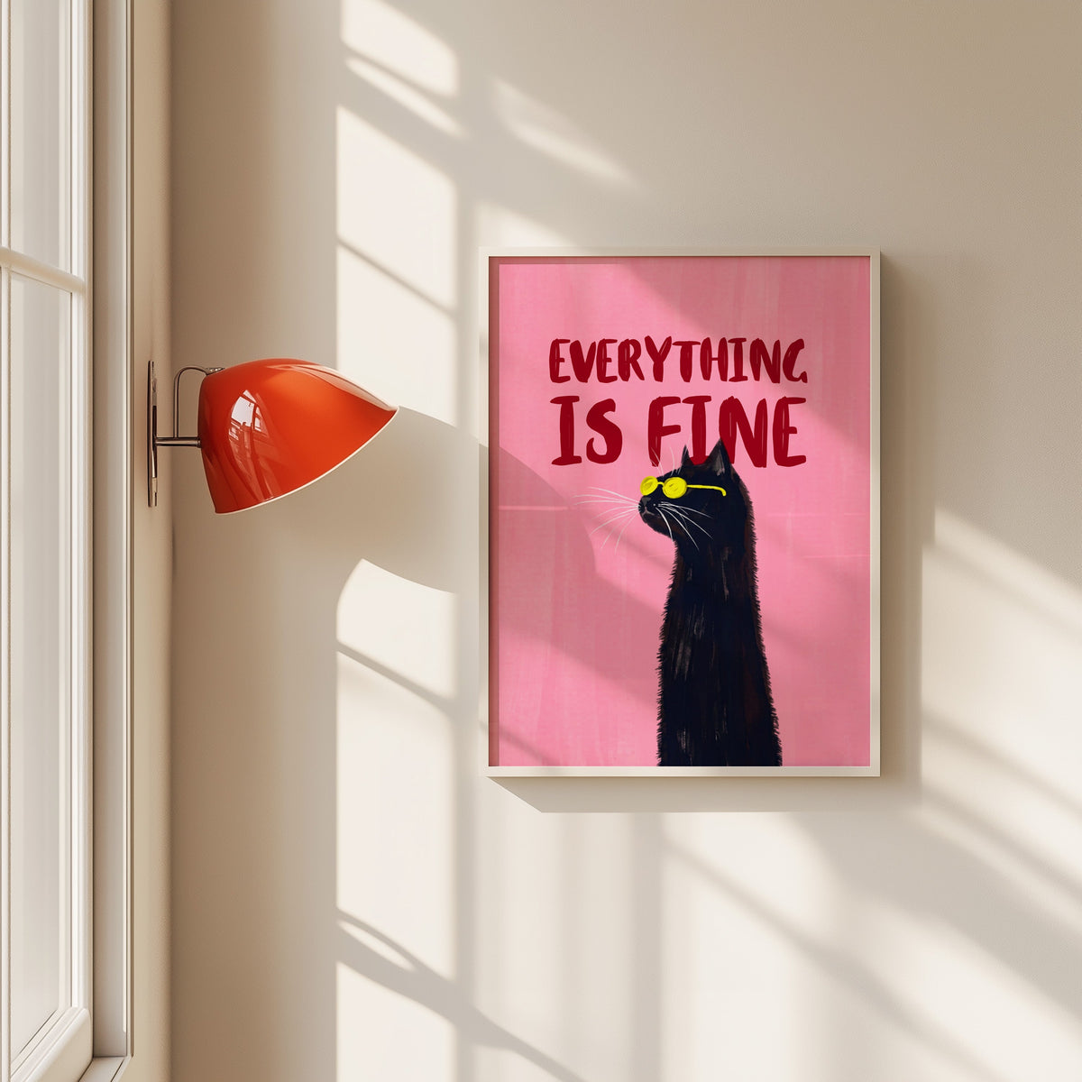Everything Is Fine black cat print in a white frame beside a red wall sconce