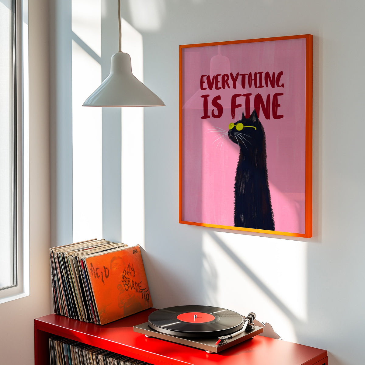 Pink black cat typography print shown in an orange frame above a red record cabinet and turntable