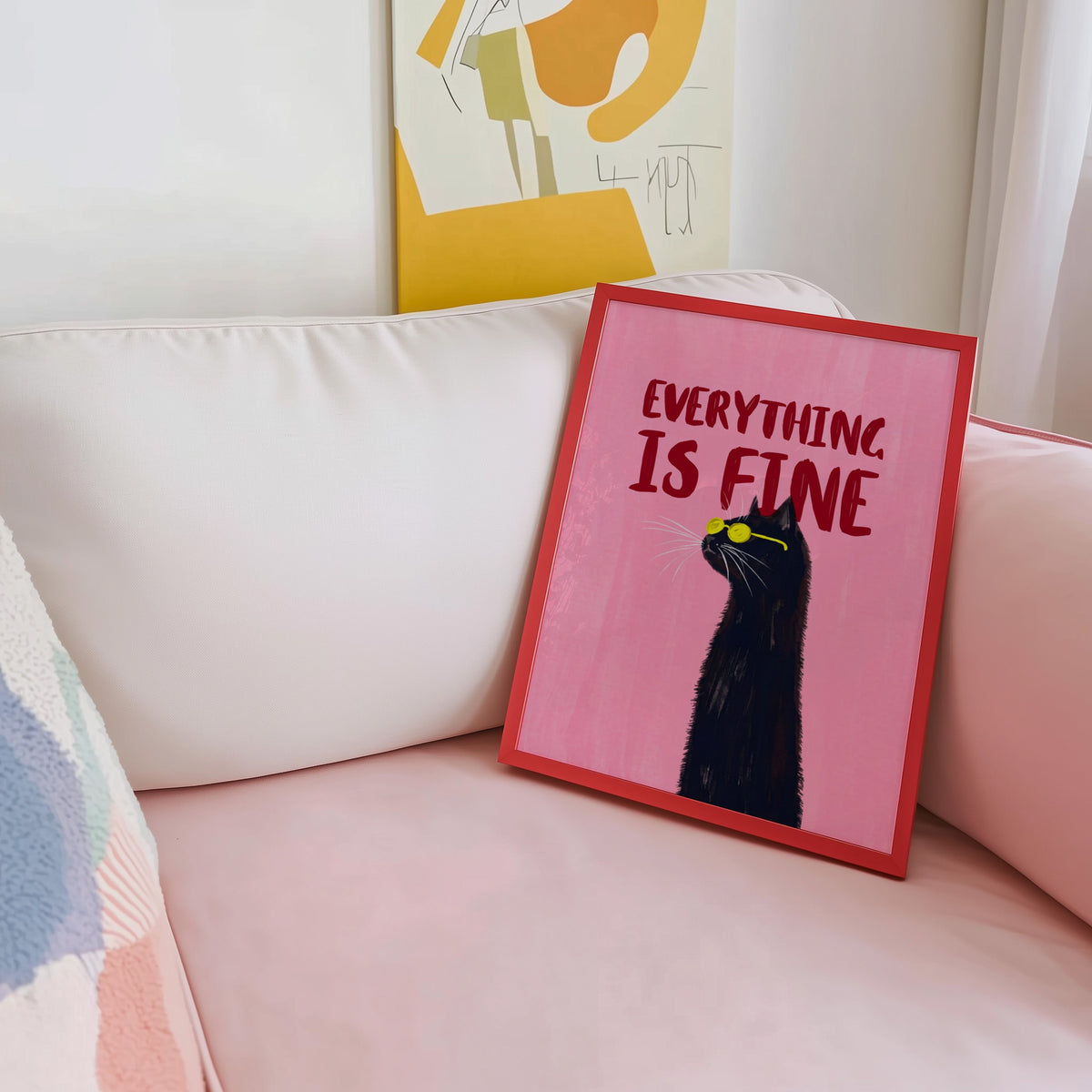 Black cat quote print shown in a red frame leaning on a blush pink sofa