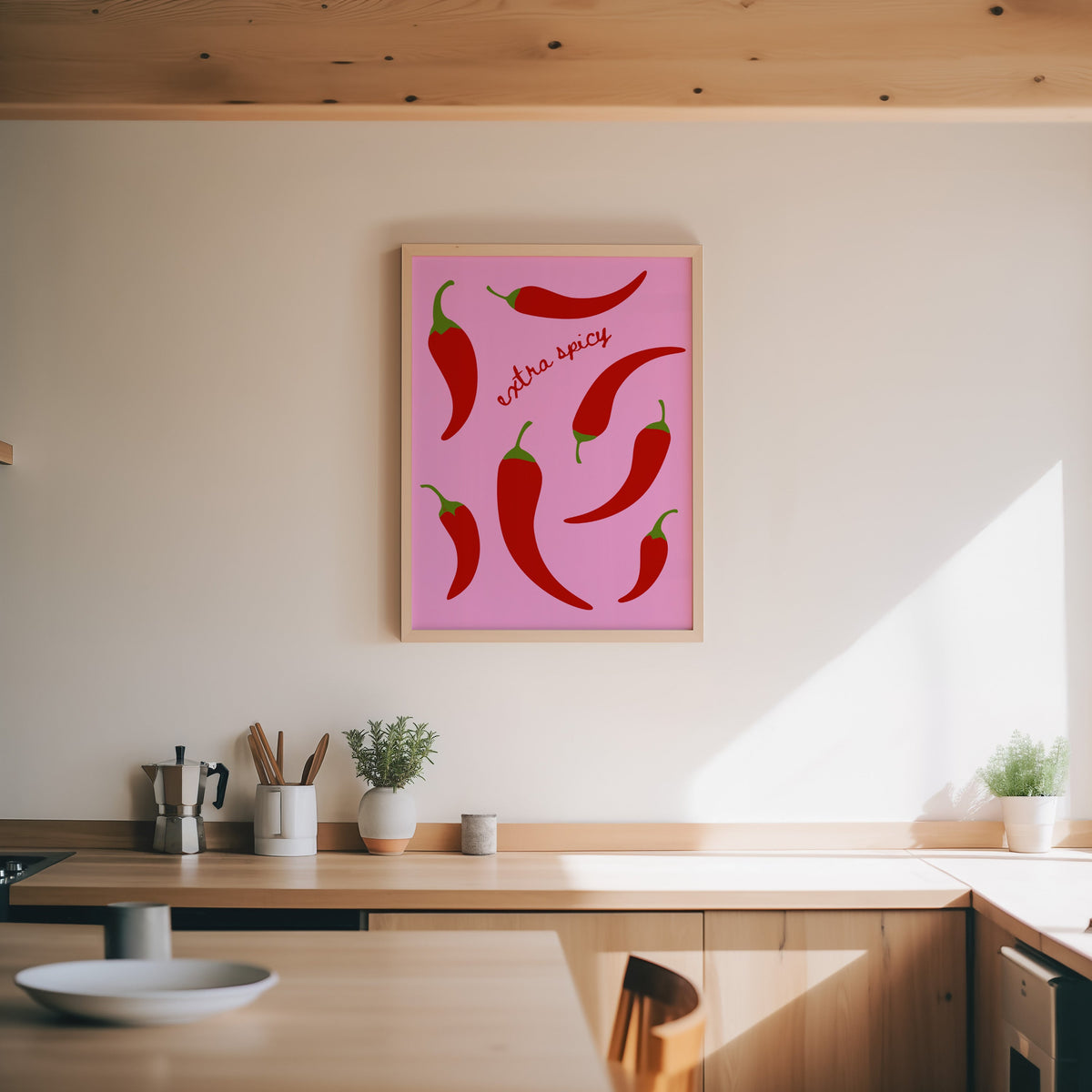Chilli pepper print in an oak frame above a wood counter with a moka pot and herbs