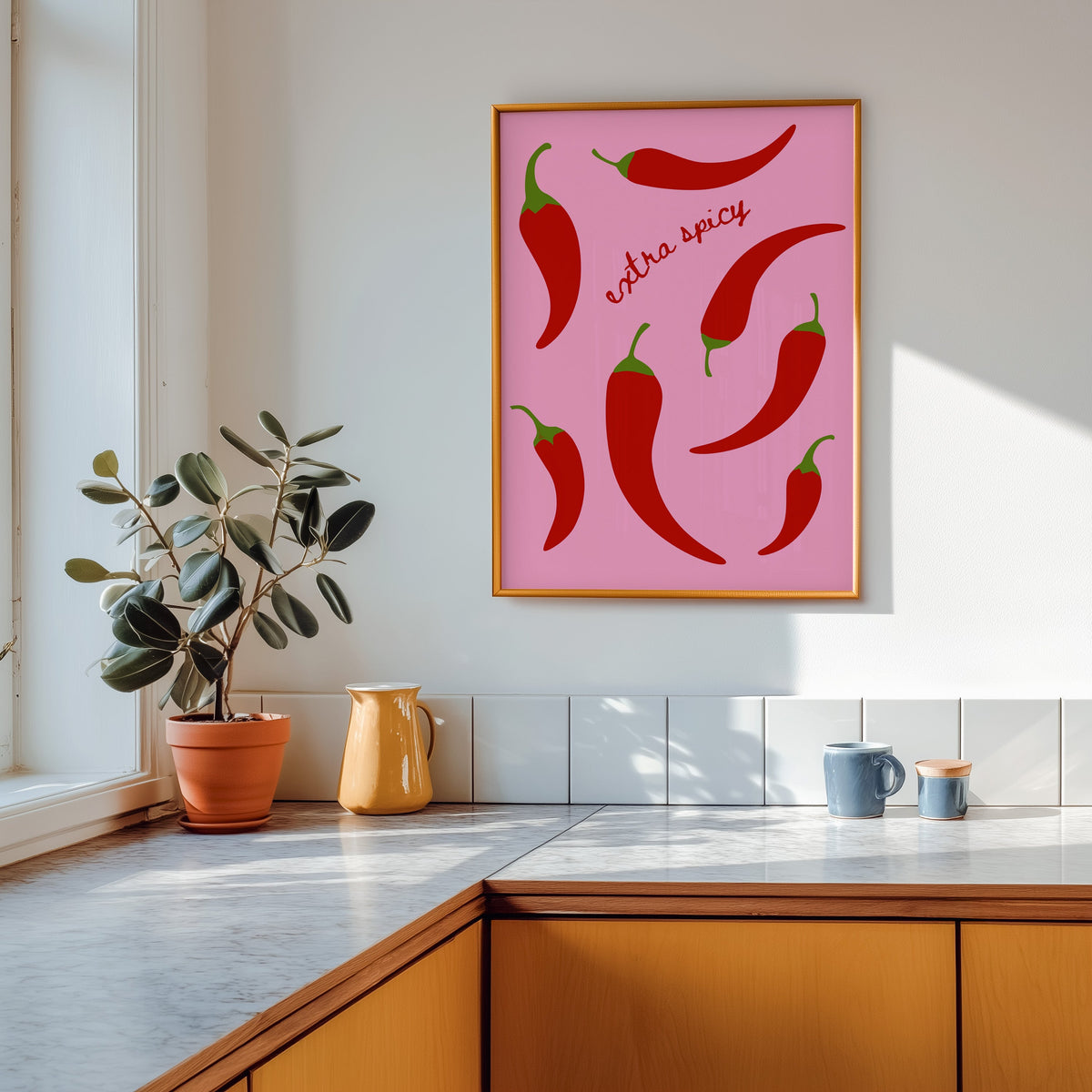 Chilli pepper print in a gold frame above a marble counter with a yellow ceramic jug