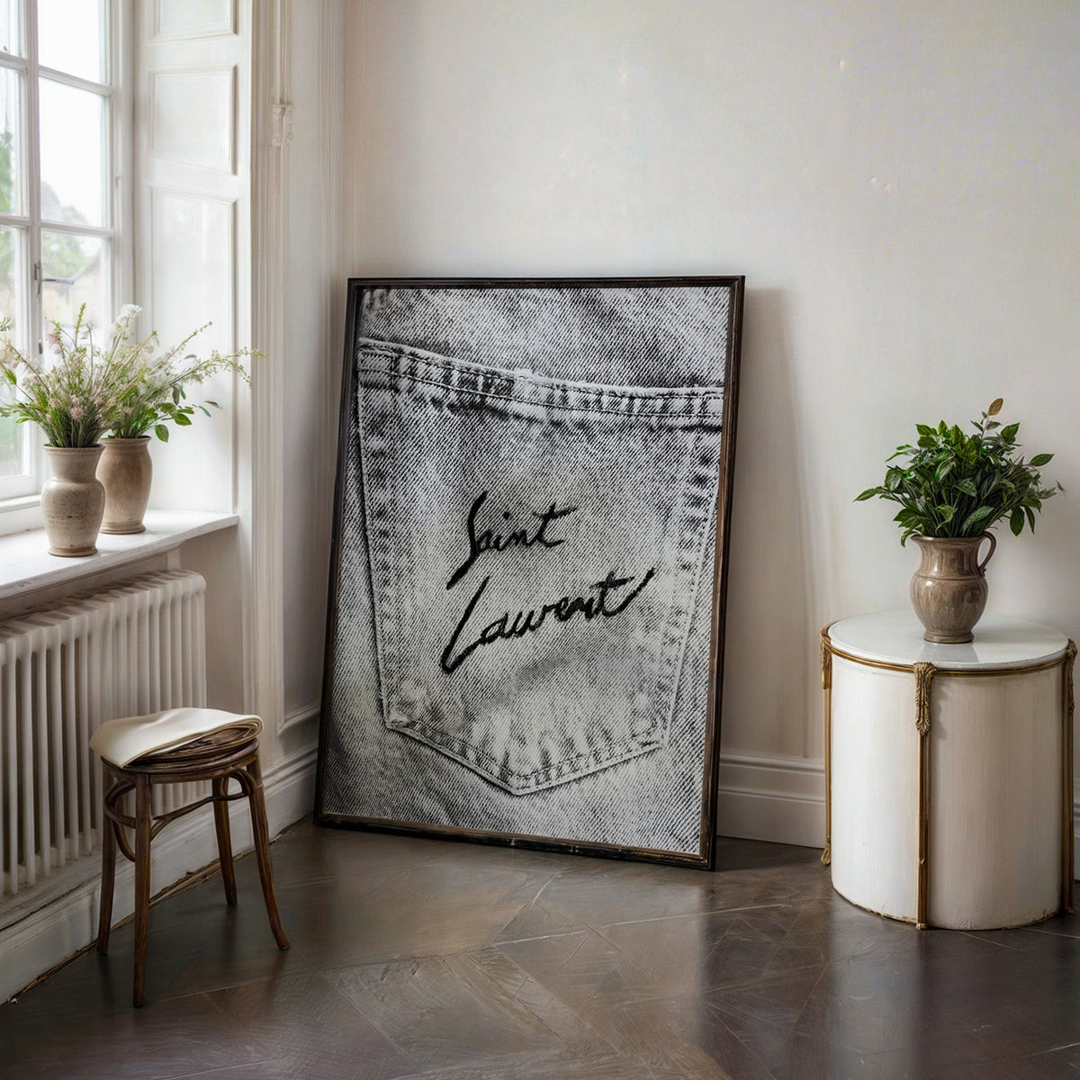Black script on faded grey denim pocket print in a black frame on a dark stone floor beside a white side table