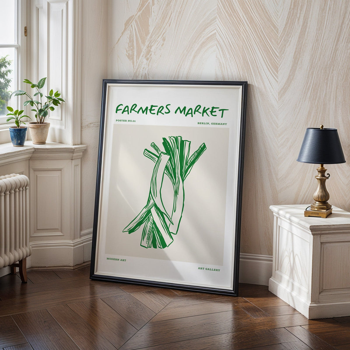 Green leeks print in a black frame on a dark herringbone floor beside a radiator