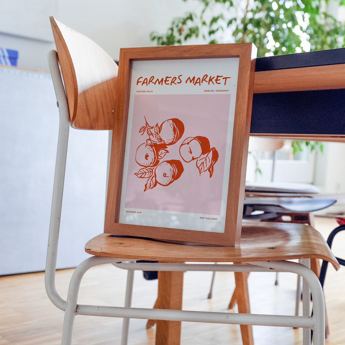 Farmers Market peaches print in a walnut frame resting on a bentwood chair in a workspace