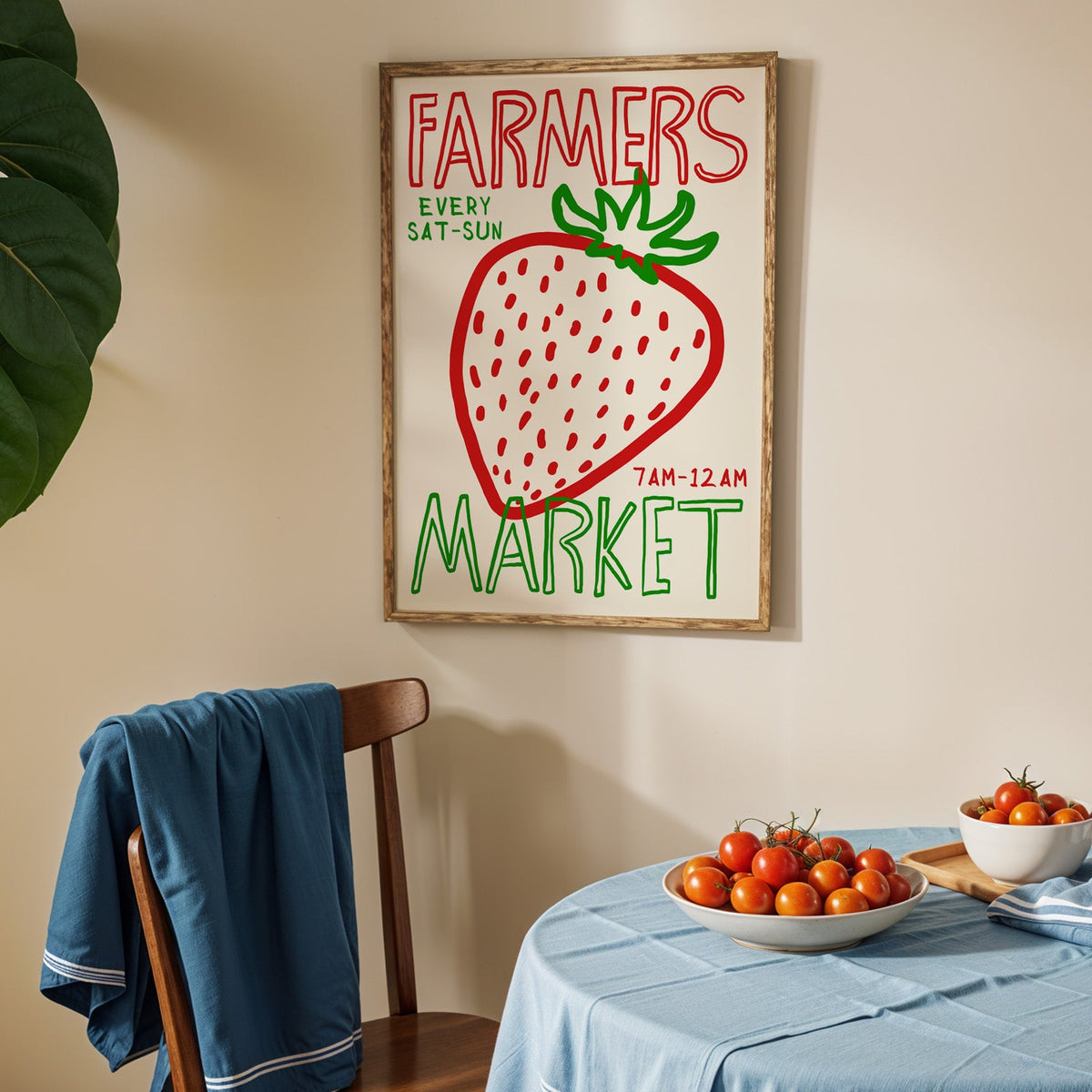 Farmers market strawberry print in an oak frame above a blue linen table with ripe tomatoes