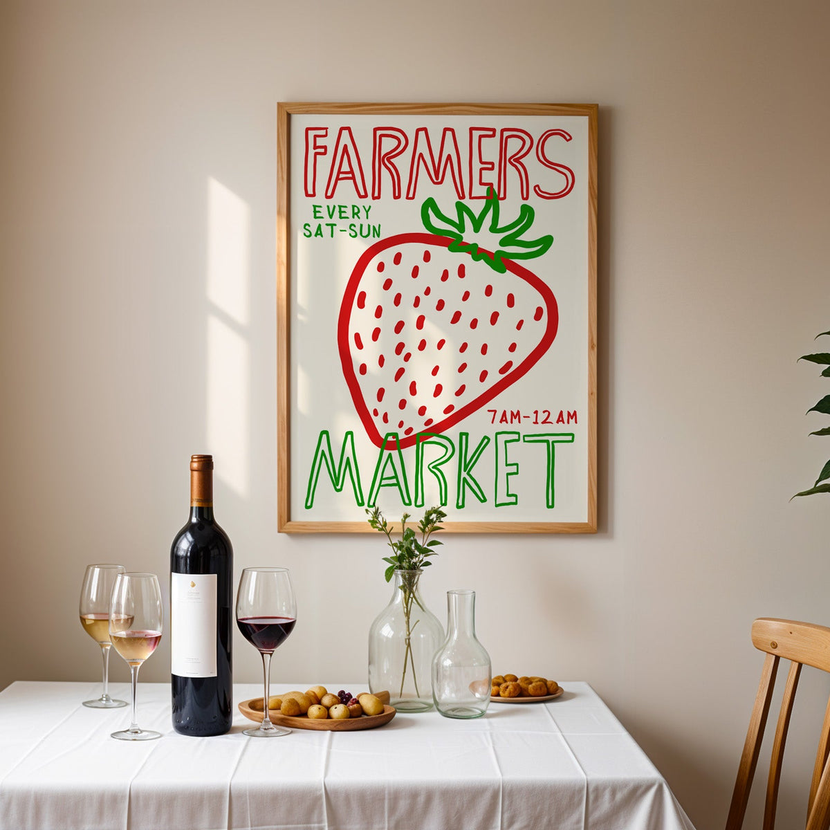 Farmers market strawberry print in an oak frame above a table laid with red wine and glasses