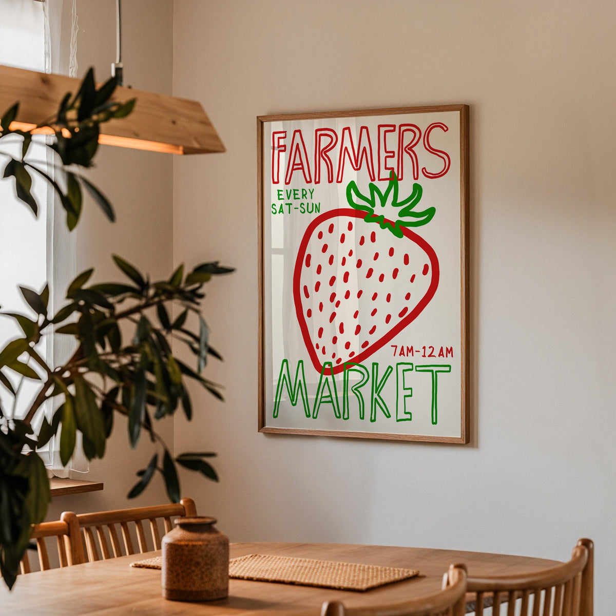 Farmers market strawberry print in a walnut frame above a dining table beside an olive tree