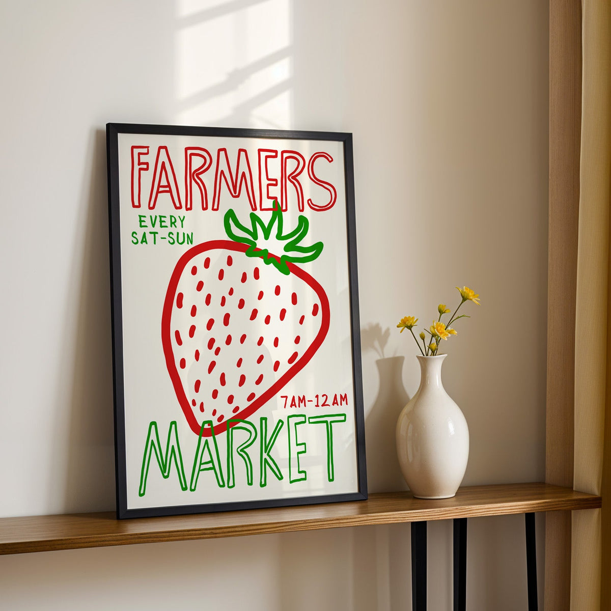 Farmers market strawberry print in a black frame on a console table with yellow daisies