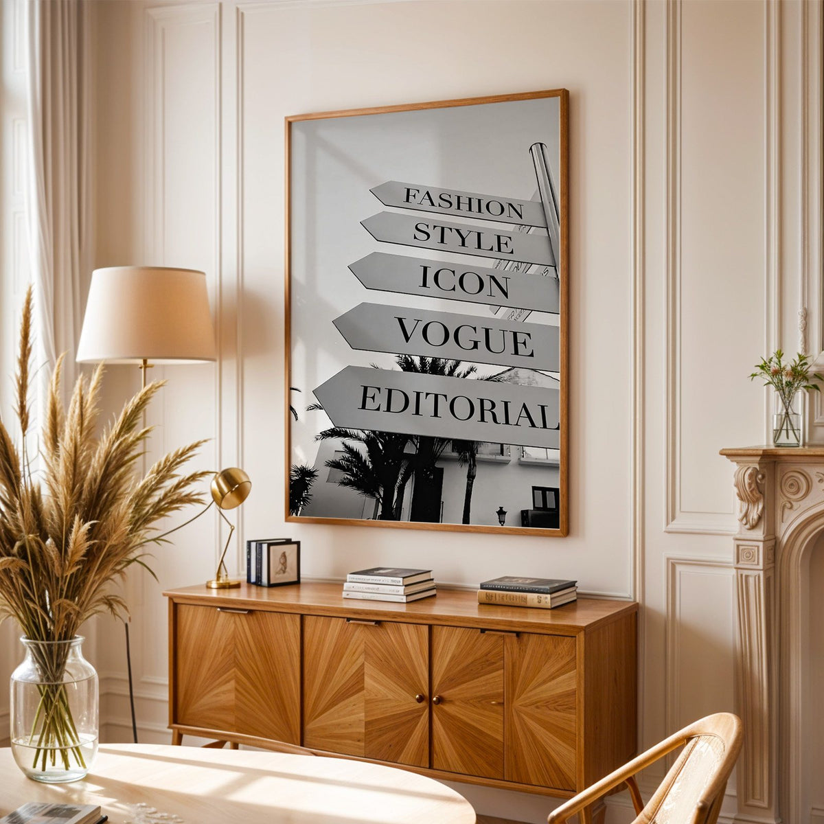 Street signpost with fashion words above palm trees print in an oak frame above a sunburst wood sideboard with pampas grass