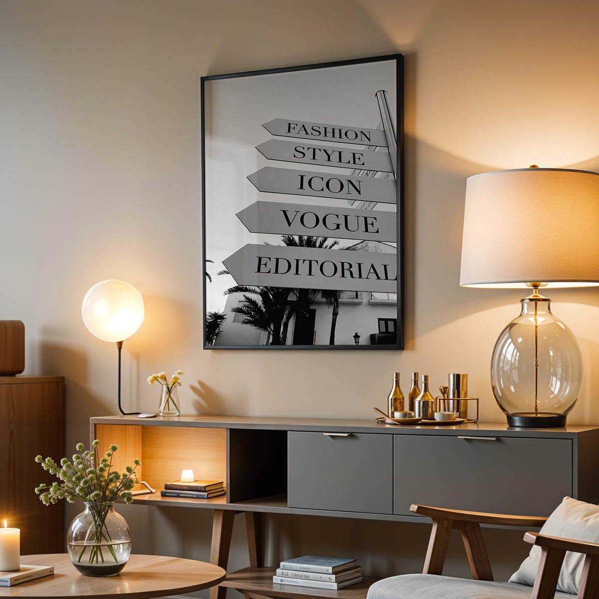 Street signpost with fashion words above palm trees print in a black frame above a grey media console with a glass table lamp
