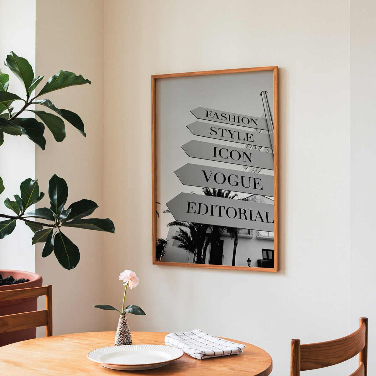 Street signpost with fashion words above palm trees print in a teak frame above a round wooden dining table