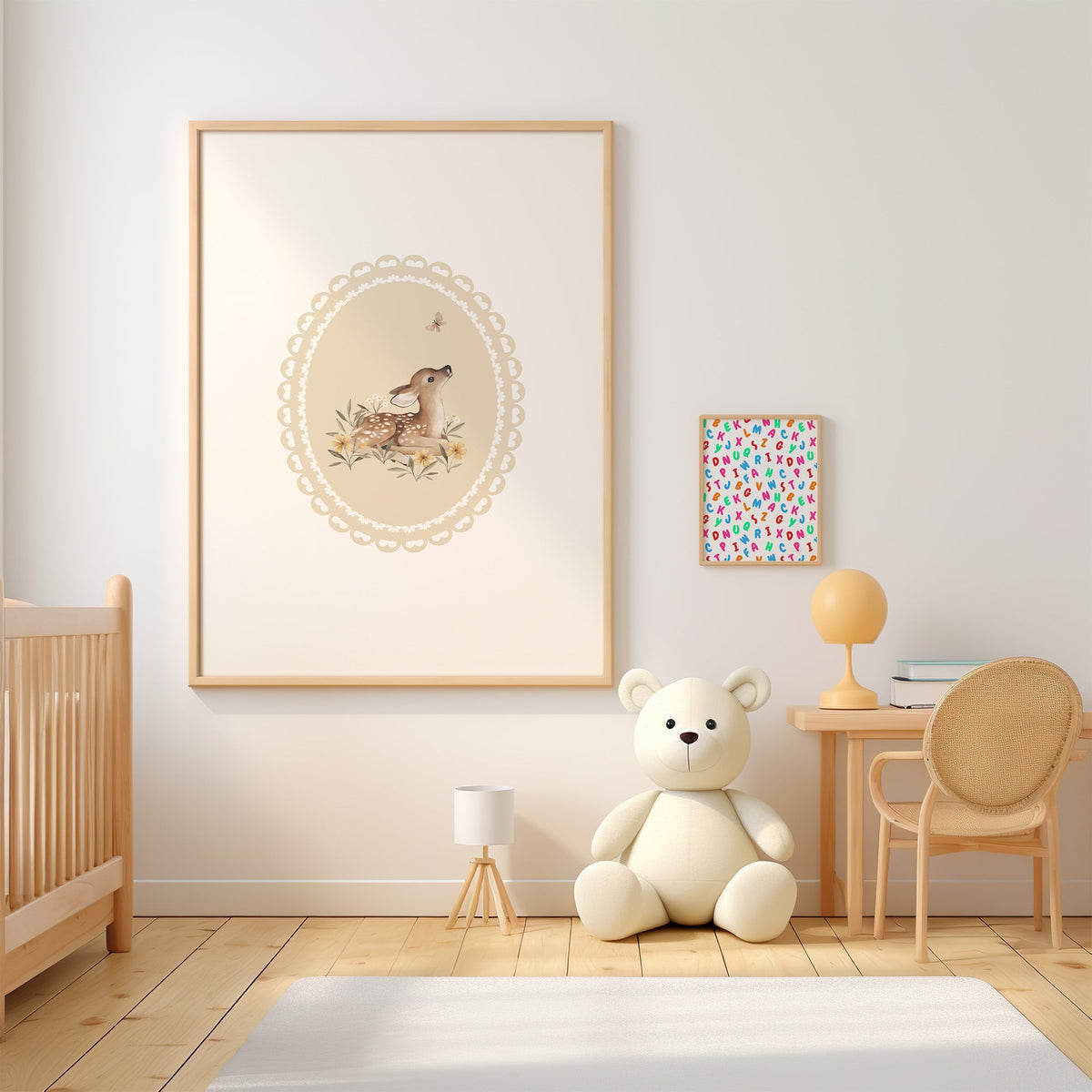 Fawn watching a butterfly in a lace oval nursery print in an oak frame above a wooden crib beside a cream teddy bear