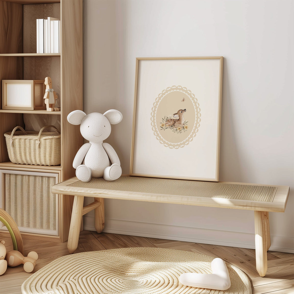 Fawn watching a butterfly in a lace oval nursery print in an oak frame on a cane bench beside a white knit plush