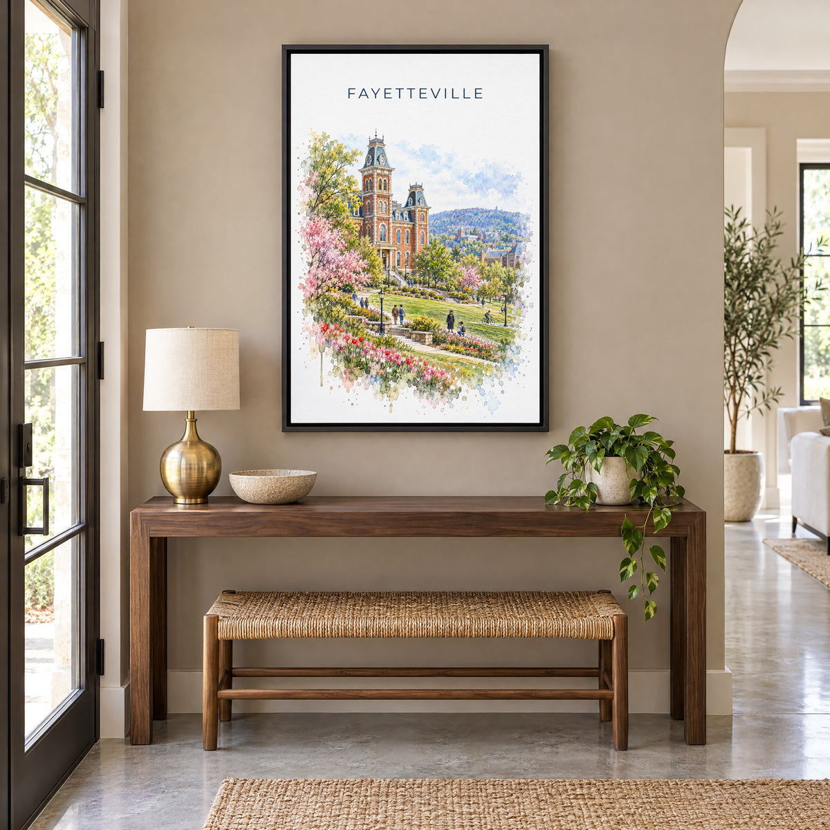 Fayetteville, Arkansas watercolor print as a black floater canvas above a walnut console and woven bench in an entryway