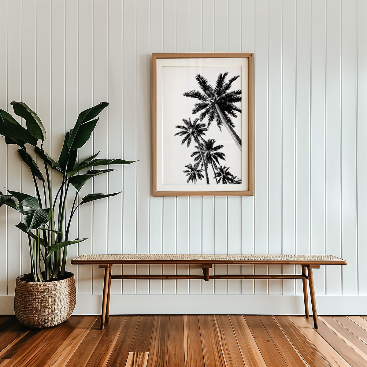 Feather leaf palms on a white sky print in a wood frame with a white mat above a cane bench