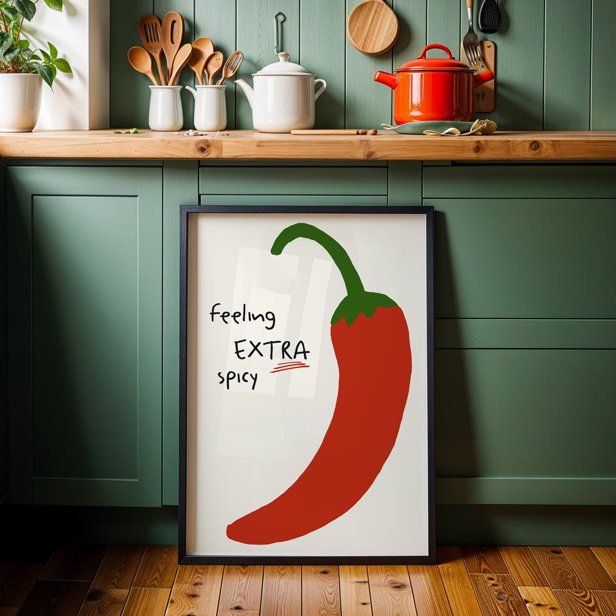 Feeling extra spicy chili print in a black frame against sage green kitchen cabinets