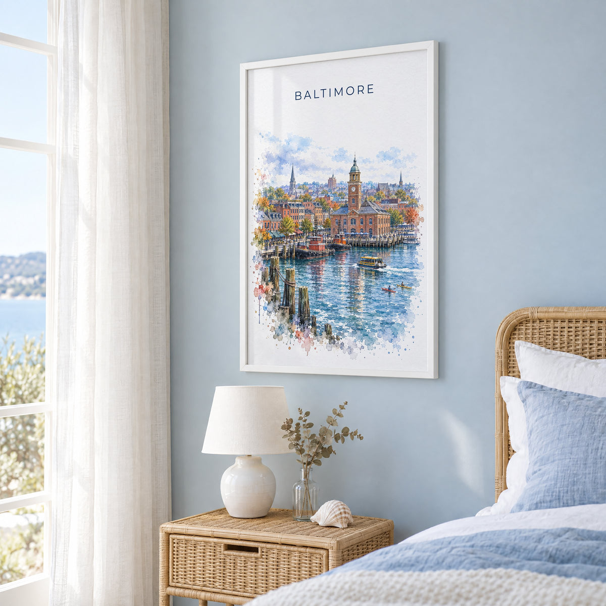 Fells Point Baltimore watercolor print in a white frame on a pale blue wall beside a rattan bed in a coastal bedroom