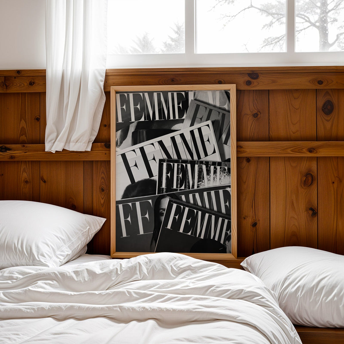 Layered FEMME magazine covers collage print in a pine frame leaning on a wood headboard over white bedding