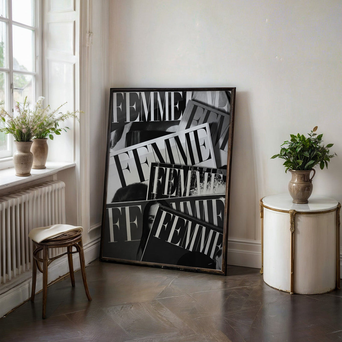 Layered FEMME magazine covers collage print in a black frame on a dark stone floor beside a white side table