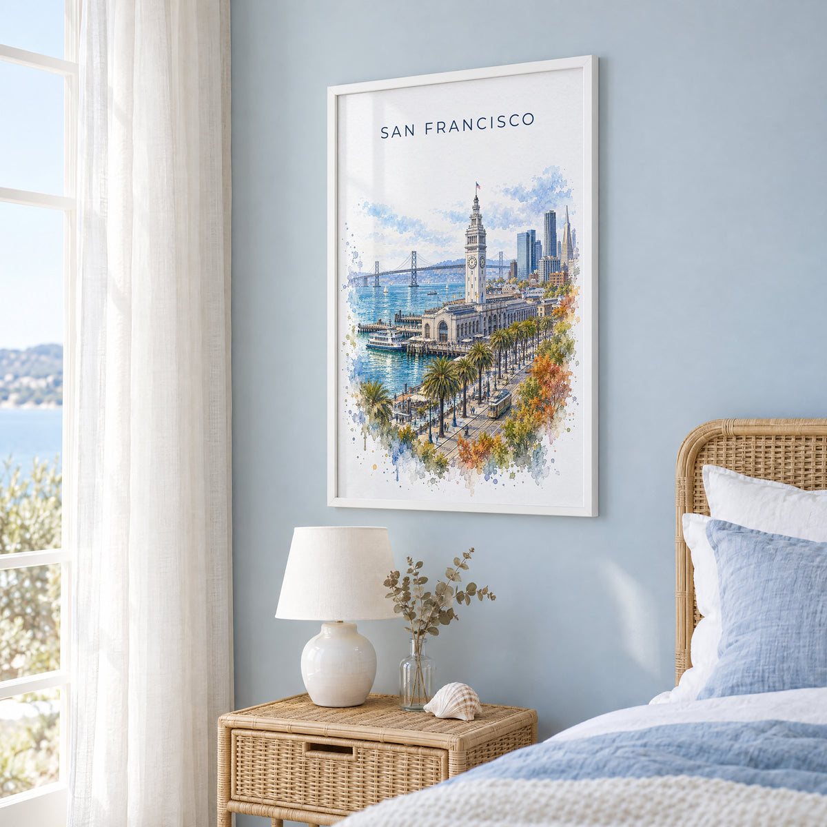 Ferry Building San Francisco watercolor print in a white frame on a pale blue wall beside a rattan bed in a coastal bedroom